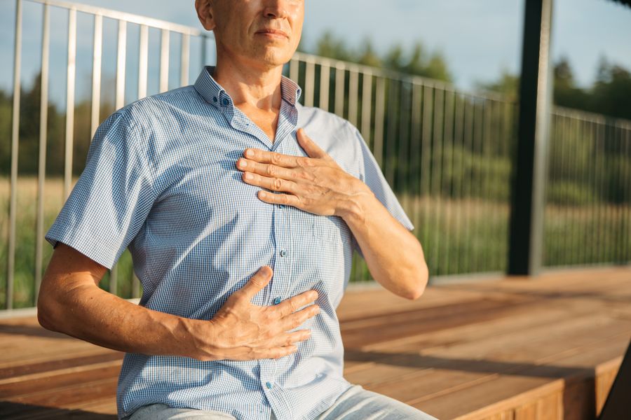 Man met één hand op zijn borst en één op zijn buik die rustig ademt