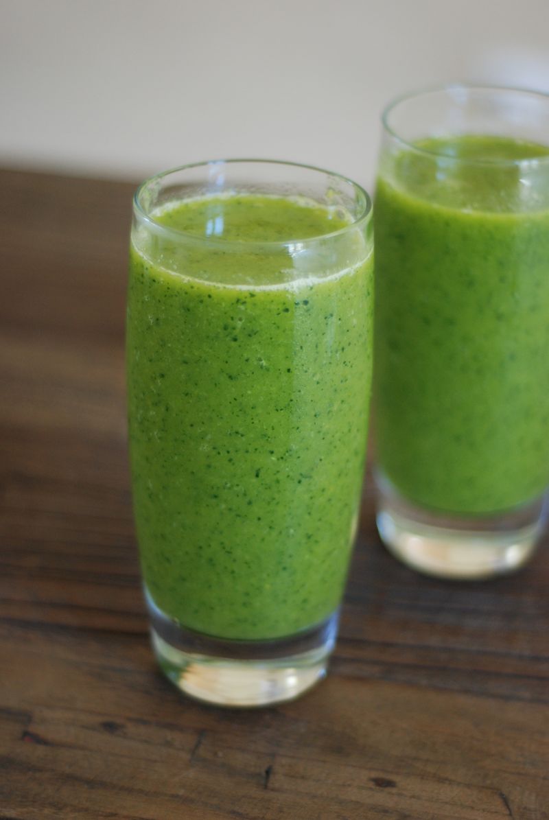 Twee glazen groene smoothie op een houten tafel